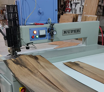 Operario preparando chapa de madera en máquina cosedora Kuper, en el taller de Enchapadora Tigre